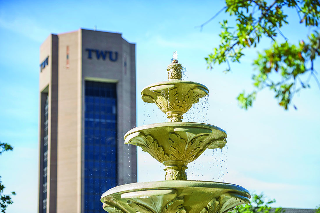 Photo of TWU Dorm in background with a fountain in foreground.