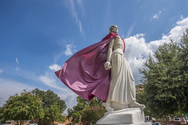 Minerva statue with maroon cape flowing in the wind off of her shoulders from an upward angle.