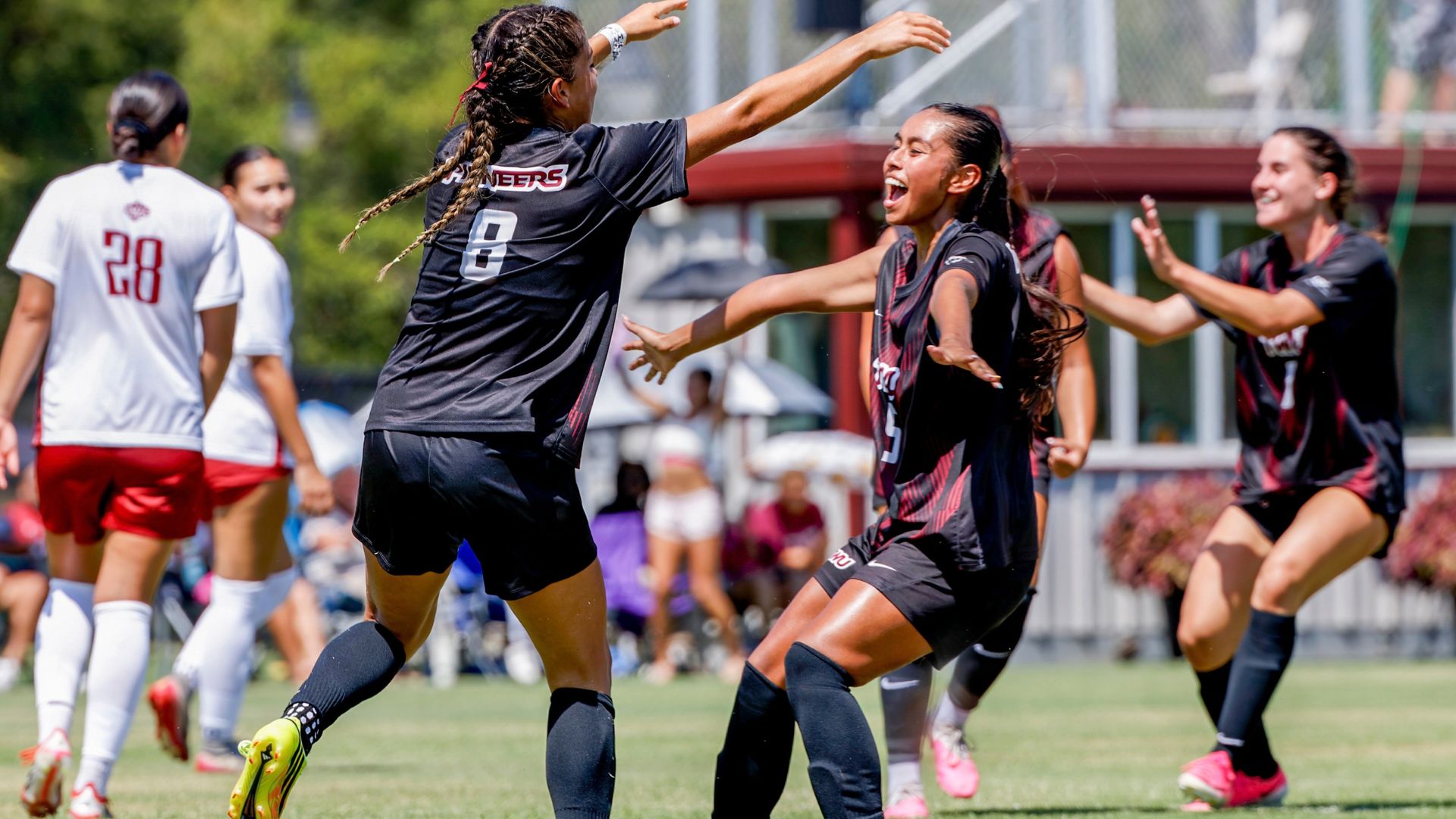Two soccer players run toward each other on field in celebration